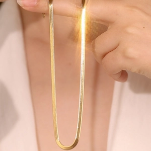 Elegant 3mm gold flat snake chain necklace in stainless steel held against white clothing