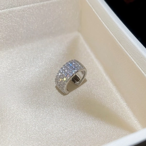 Macro shot of silver metal ring with sparkling clear stones set in a beige silk jewelry box