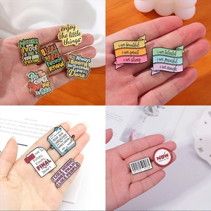 Detail showing various enamel inspirational quote pins on a textured fabric background