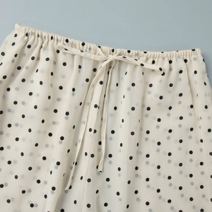 Close-up of white polka dot pants with elastic waistband and decorative drawstring