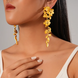 Boucles d'oreilles fleurs et feuilles dorées style vintage portées par un modèle