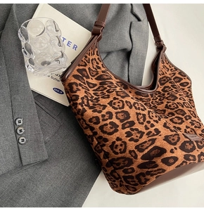 Close-up of leopard print tote bag with dark brown strap and brand label detail