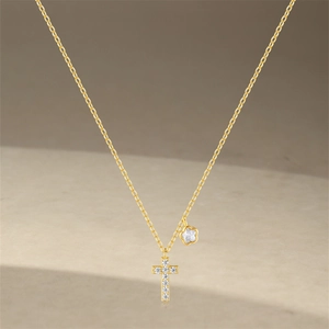 Close-up of a delicate gold flower and cross pendant necklace with sparkling crystals