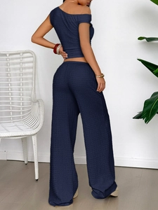 Detailed texture of navy blue one-shoulder crop top and matching wide-leg trousers