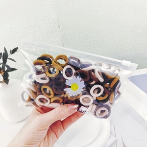 Elastic seamless hair ties in neutral tones stored in a daisy print zipper pouch