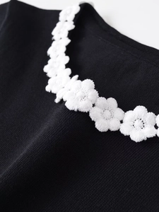 Close-up of elegant 3D white floral embroidery on a black knit round neck T-shirt detail