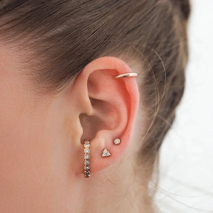 Close-up of rose gold ear cuff and cubic zirconia studs on a model's ear