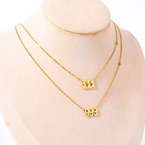 Detail of gold angel number necklaces 111 and 999 with small colorful gemstones