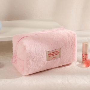 Detailed close-up of pink plush makeup bag featuring embroidered text and zipper closure