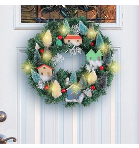 Illuminated Christmas wreath with wooden houses and red berries on a white door
