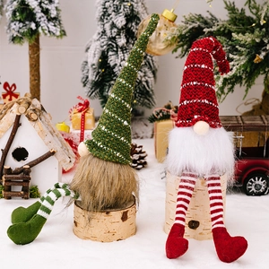 Close-up of knit Christmas gnomes with striped legs on a snowy festive background