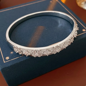 Detail view of silver flower bangle with zircon accents on a blue luxury jewelry gift box