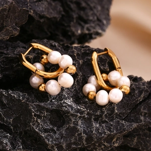Détail de boucles d'oreilles U plaquées or 18K avec perles d'eau douce sur pierre noire
