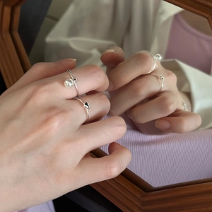 925 silver ring featuring a white pearl and black heart gem reflected in a wood mirror