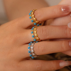 Anelli minimalisti in oro e argento con perline turchesi sulla mano di modella