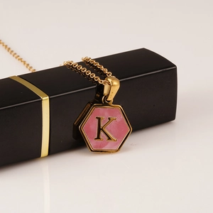Detail of pink hexagonal shell pendant with letter K on golden stainless steel chain