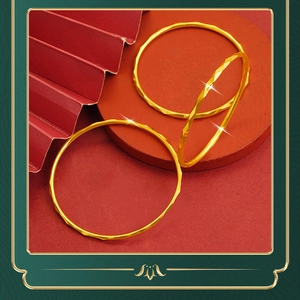 Detail of three gold geometric bangles featuring diamond-cut facets on a red fan backdrop