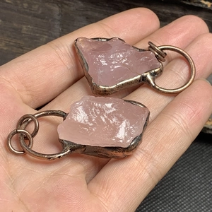 Dettaglio dei ciondoli in quarzo rosa fatti a mano con finitura in bronzo e trama naturale