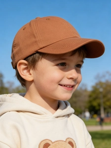 Close-up of caramel kids baseball cap featuring a plush teddy bear hoodie detail