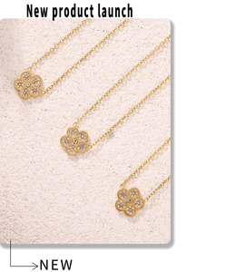 Macro shot of three gold flower necklaces with pavé zircons on a textured stone surface