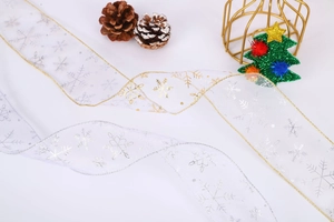 Close-up of sheer Christmas ribbons with gold and silver snowflakes and pine cones