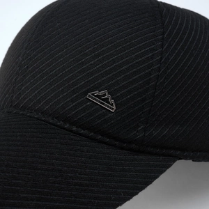 Detail einer schwarzen Winter-Basecap mit silbernem Metalllogo und strukturierter Textur