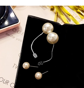 Detail of elegant pearl fringe earrings with silver metal chains on a black display
