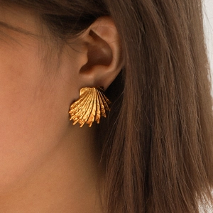 Close-up of a 18k gold-plated stainless steel shell earring worn by a female model