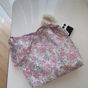 Flat lay of floral cotton tote bag with pink and purple flower pattern on white desk