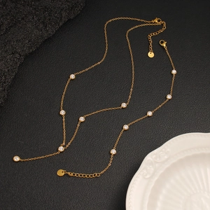 Exquisite gold zircon necklace with circular clear gemstones on a dark textured surface