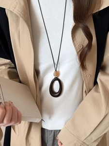 Detail of amber bead and resin oval pendant on a black cord necklace for women
