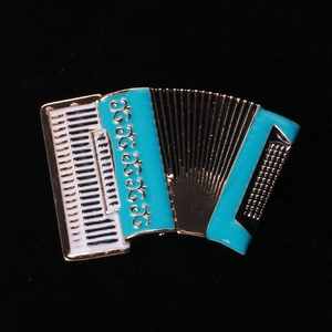 Detailed close-up of a gold-toned accordion brooch with white and teal enamel finish