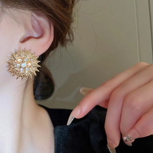 Boucles d'oreilles tournesol dorées avec cristaux portées pour un style élégant