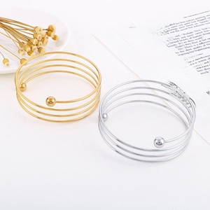 Detail view of multi-layer spiral bracelets in gold and silver with elegant ball charms