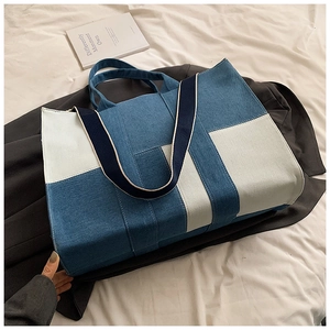 Detail of blue and white canvas tote bag with reinforced stitching and ribbon handles