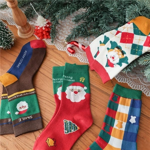 Festive Christmas cotton crew socks with Santa Claus and holiday patterns on wood background