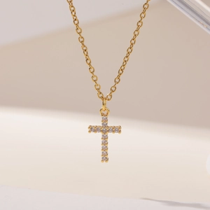 Detailed close-up of a gold cross pendant necklace featuring shimmering cubic zirconia stones