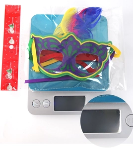 Detail shot of carnival feather mask on electronic scale showing weight of 21.8g