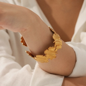 Detail eines 18K vergoldeten Edelstahlarmbands mit Ginkgoblättern am Handgelenk des Models