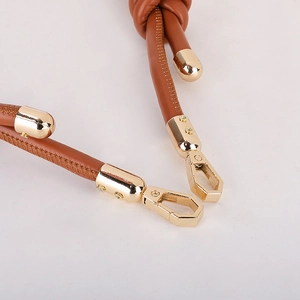 Adjustable brown leather bag strap with gold metal buckles on a white background