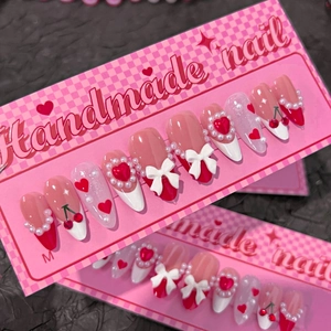 French red tip press-on nails with 3D bows, cherry art, and pearls on a display card