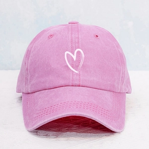 Close-up of pink washed cotton baseball cap featuring a white printed heart embroidery