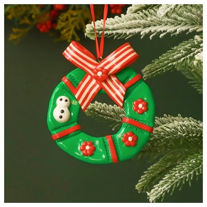 Miniature Christmas wreath ornament with red bow and snowman hanging on a frosty branch