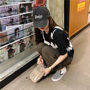Mannequin en librairie tenant une trousse de toilette en toile à carreaux marron rétro