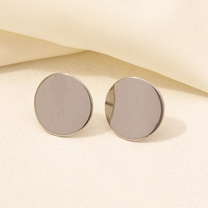 Macro shot of minimalist silver round stud earrings featuring a smooth matte finish on metal