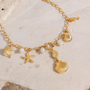 Close-up of golden ocean charms and white pearls on a stainless steel chain necklace