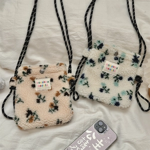 Dettaglio di mini borse in peluche a fiori con chiusura a scatto e tracolla a righe