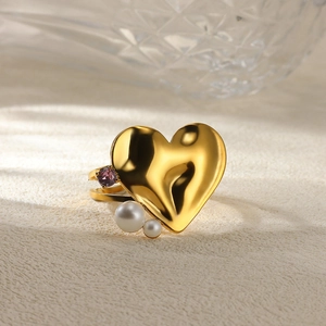 Detailed shot of heart ring with white pearls and purple gemstone on gold metal