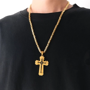 Detailed view of layered gold cross pendant with woven chain on black shirt