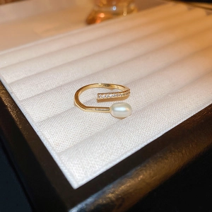 Detail of adjustable gold dragon ring with marquise pearl and zircon accents in a box